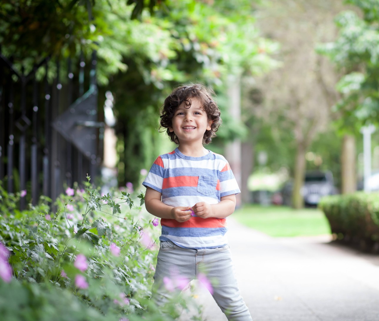 Little boy giggling on the side walk looking at the camera