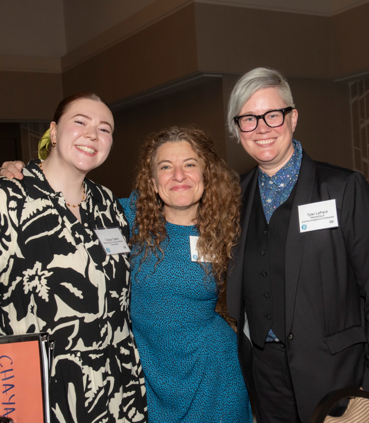 Three JFS employees side hugging for a picture at an event