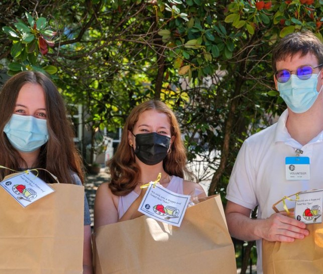Three teens wearing masks holding large brown paper bags