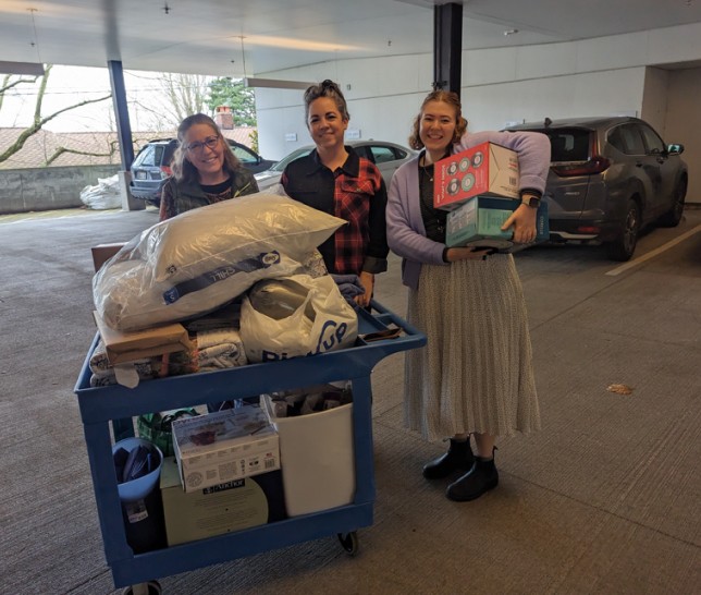Three women with donations in a parking garage