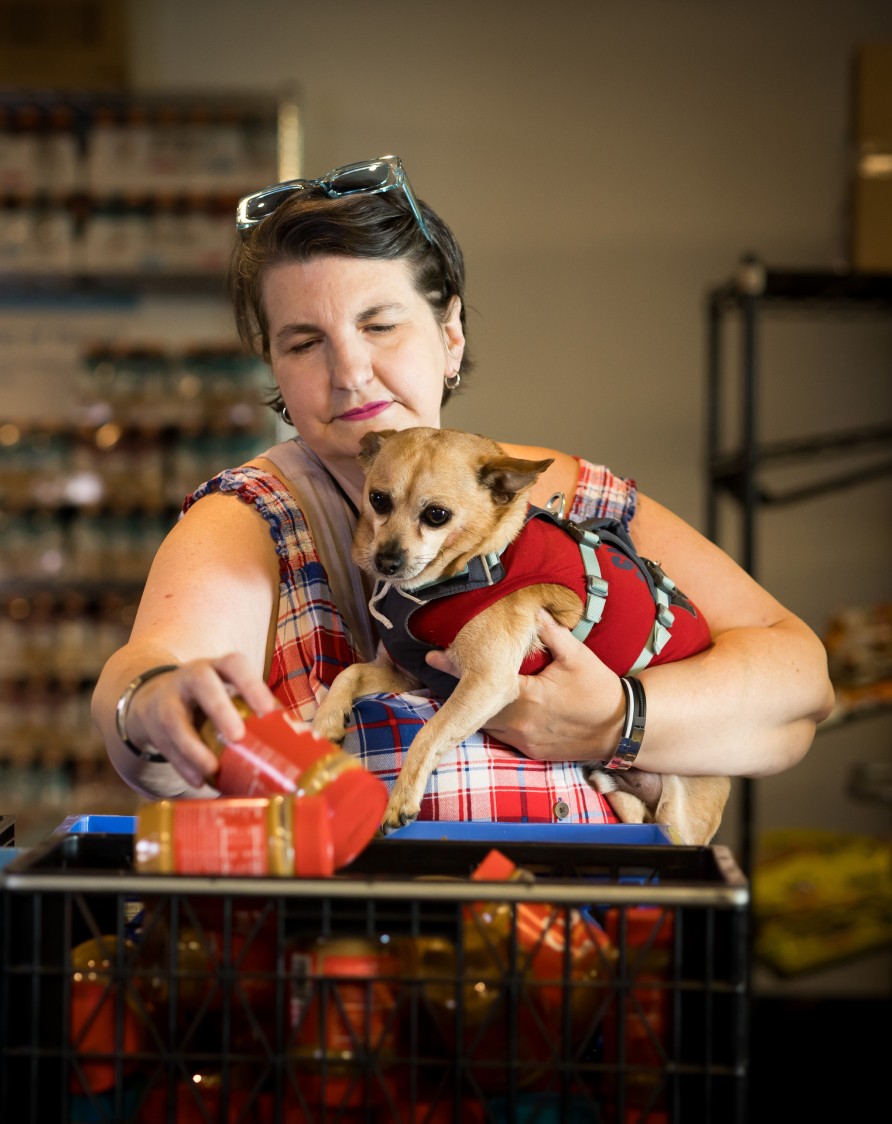 Woman holding her dog as she picks out fruit at the Polack Food Bank