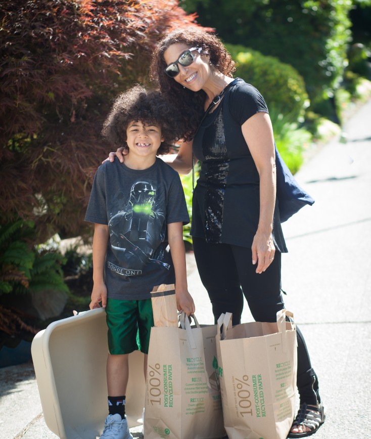 Mother hugging son outside with bags of groceries next them