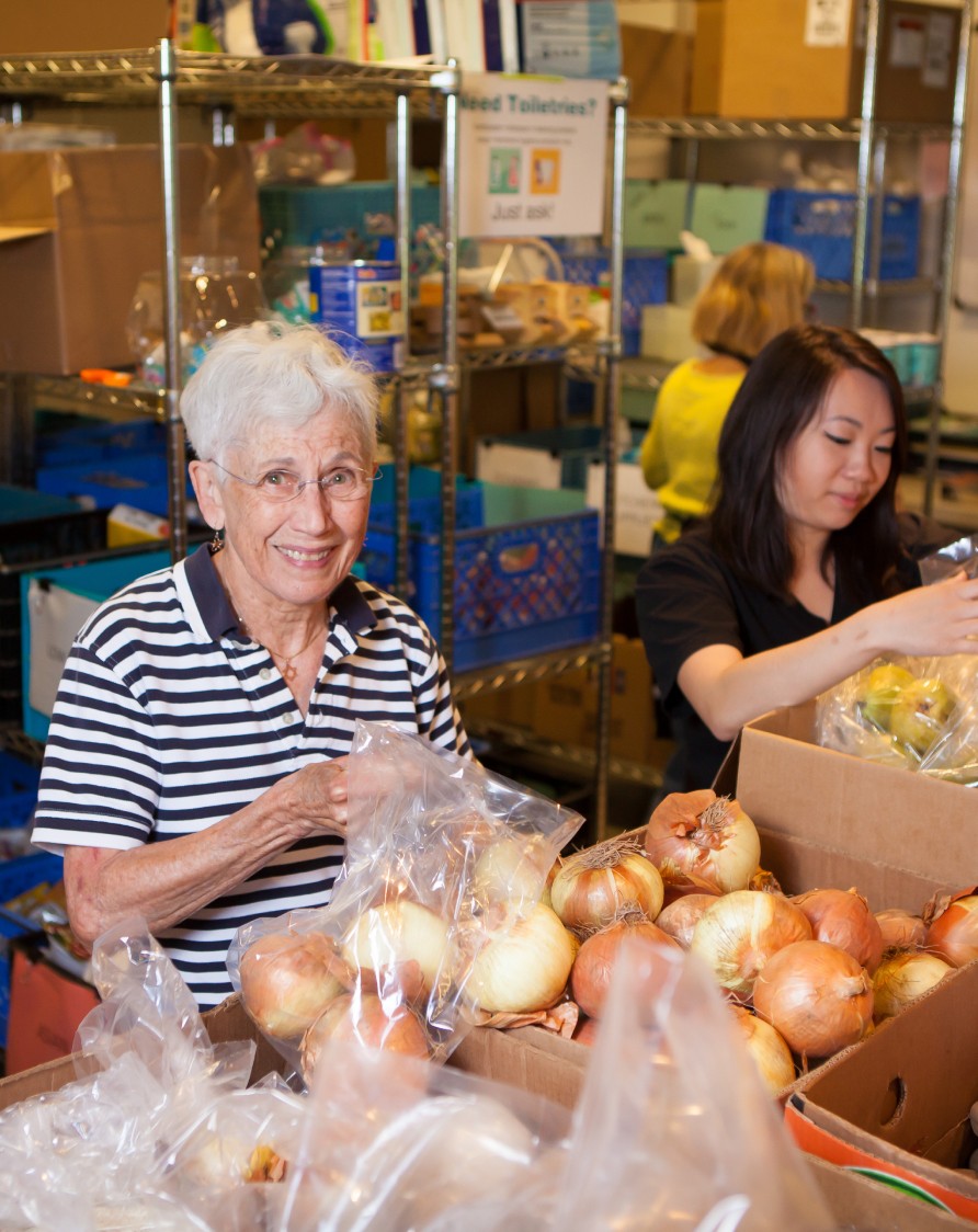 Two women picking through veggies or fruit at the Polack Food Bank