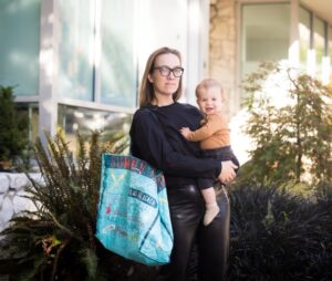 Woman holding her son with a recyclable bag on arm