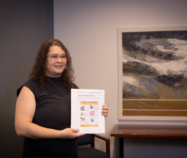 Woman holding a paper on Abuse and Power in a room