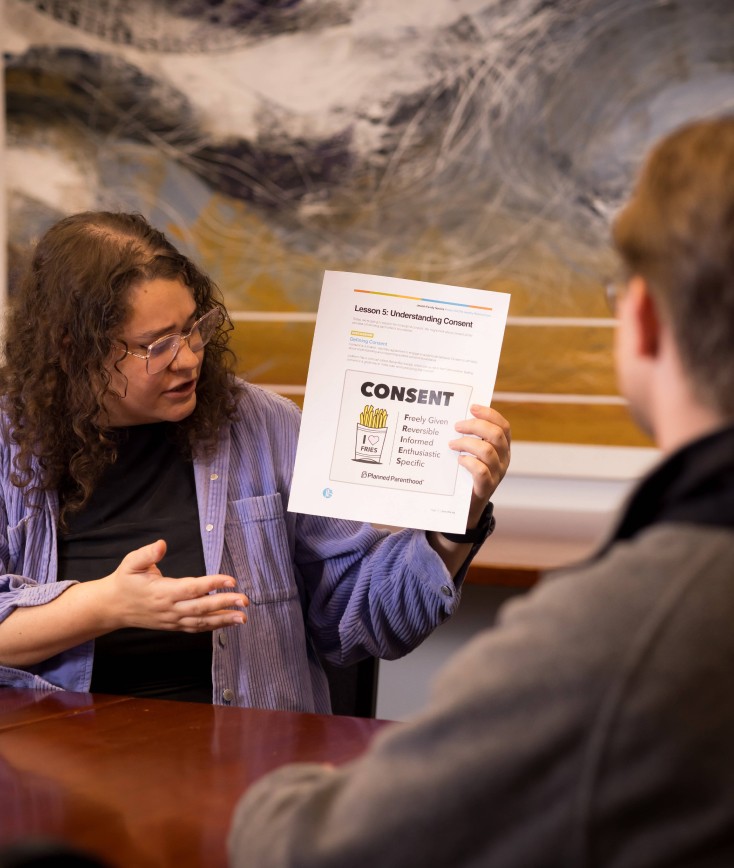 Woman sitting down at a conference table holding and looking at a paper on Abuse and Power in a room