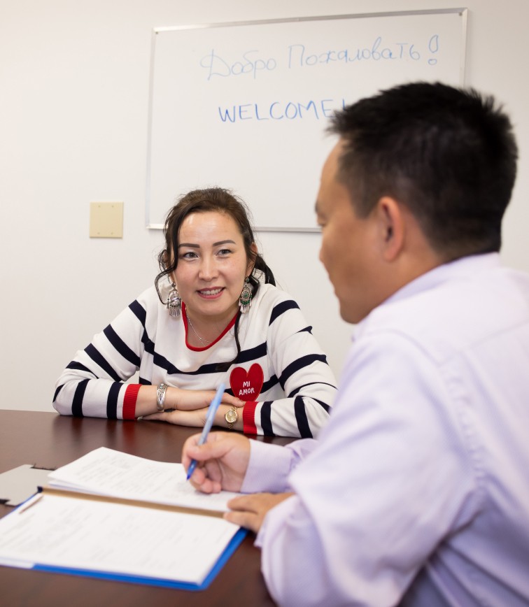 Woman wearing a striped shirt sitting with a man at a table as he look at documents