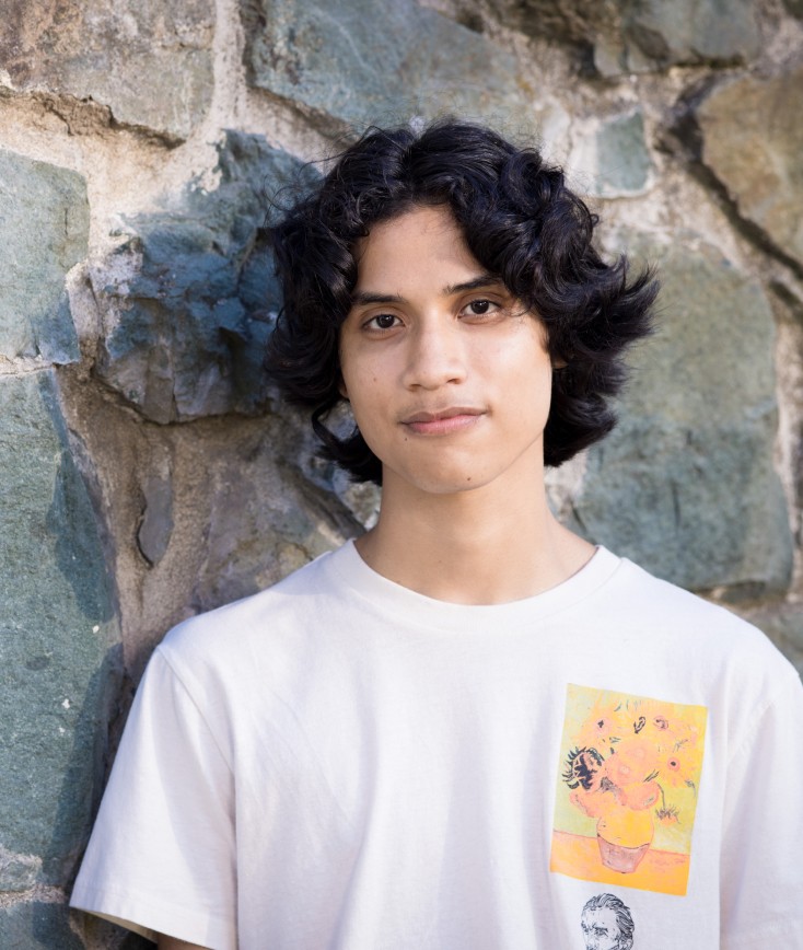Portrait of a young man leaning against a stone wall