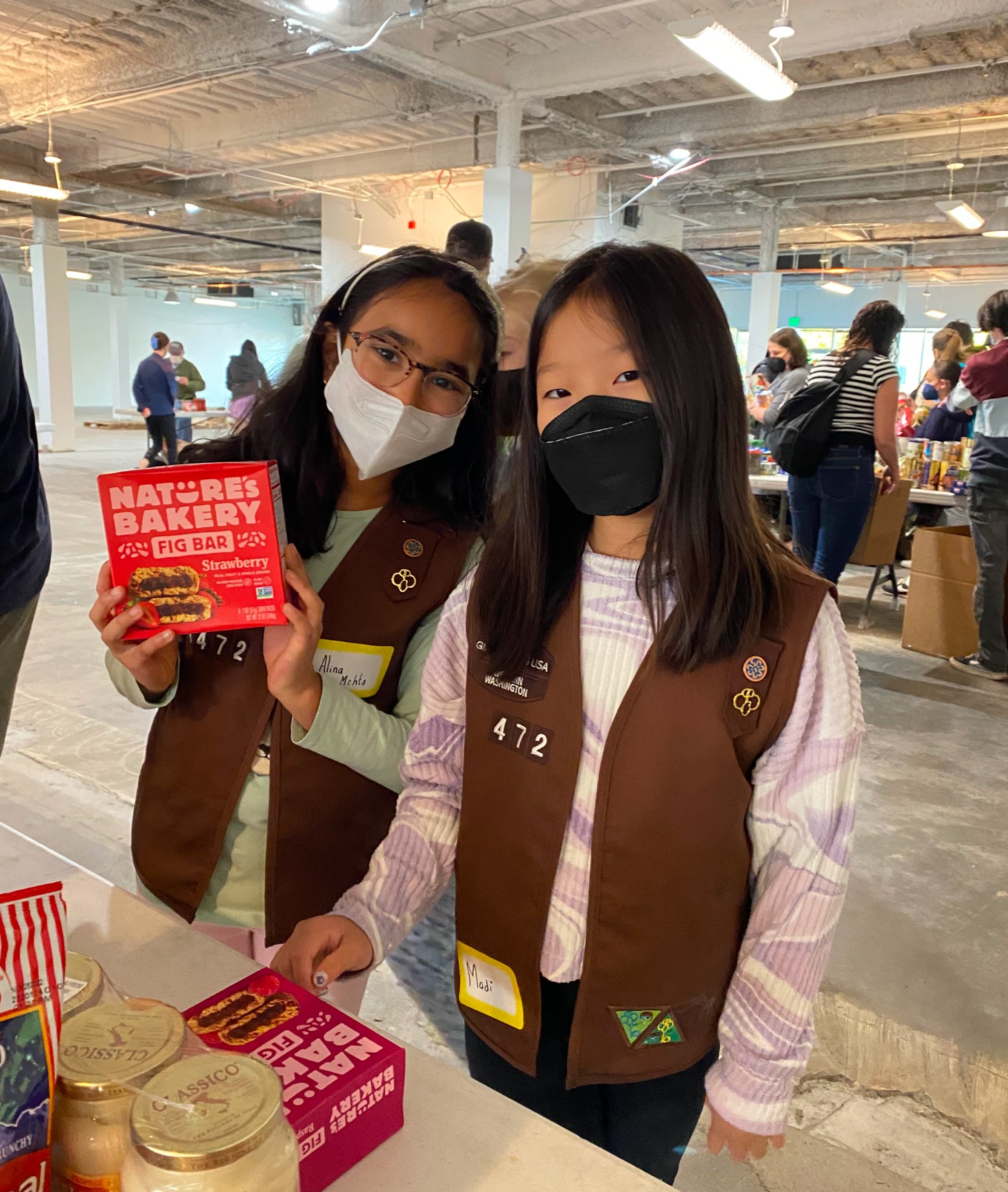 Two Girl Scouts wearing masks holding Nature Bakery Fig Bars