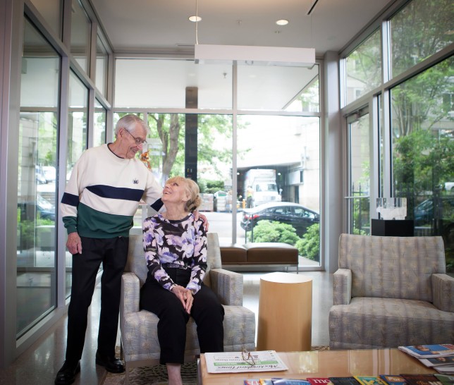 Older couple inside a lobby looking up at one another.