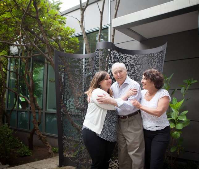 Three generations of family members hugging outside of a building