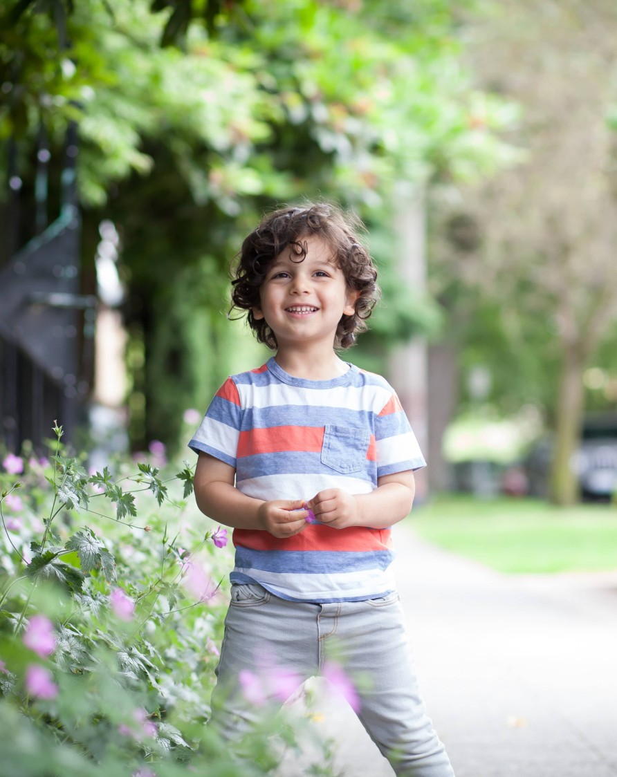 Little boy giggling on the side walk looking at the camera