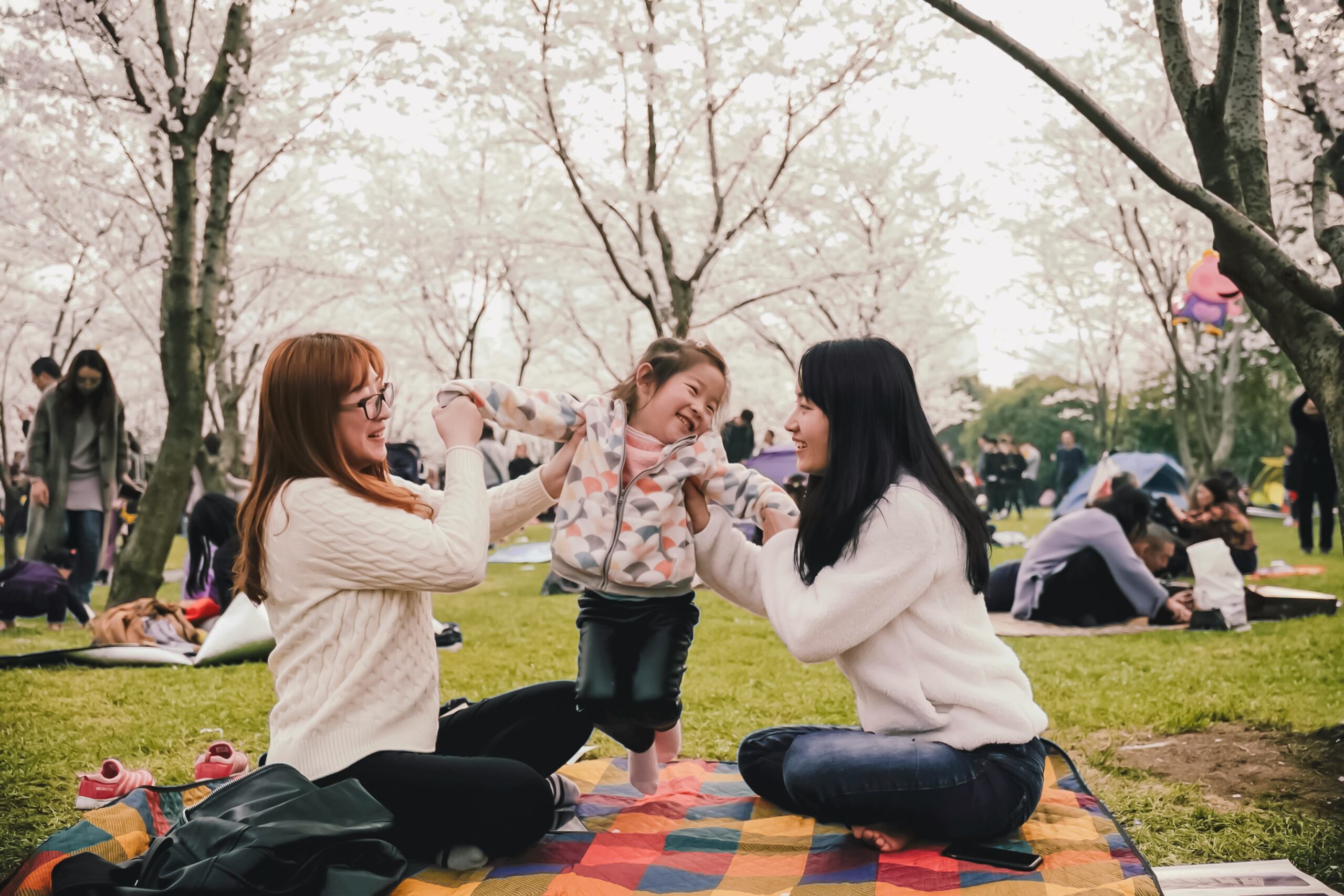 two women at a picnic in the park with a young child