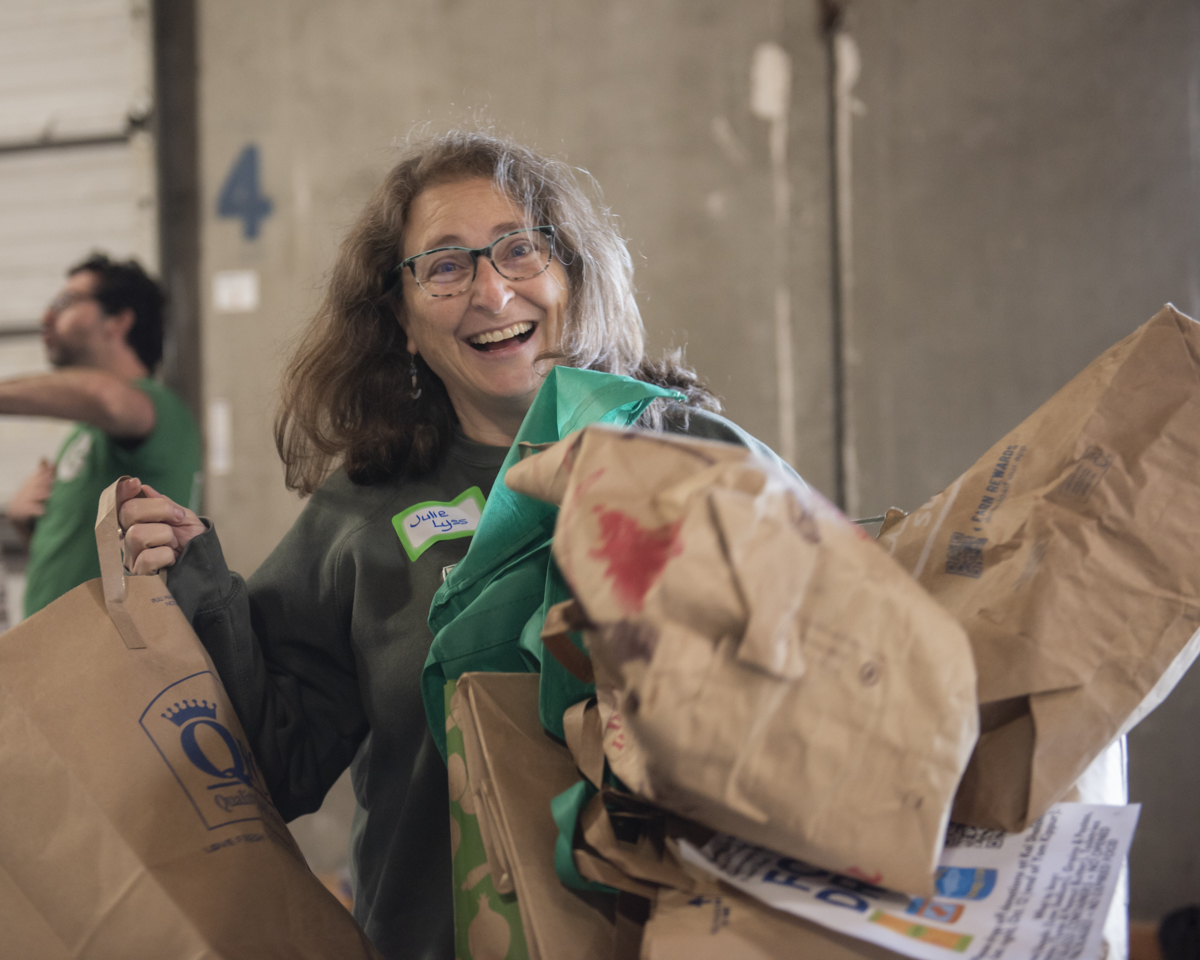 woman at food sort event holding many bags of donations