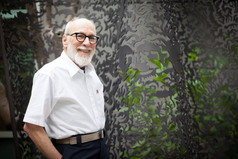 older gentleman standing in front of a Hebrew mural