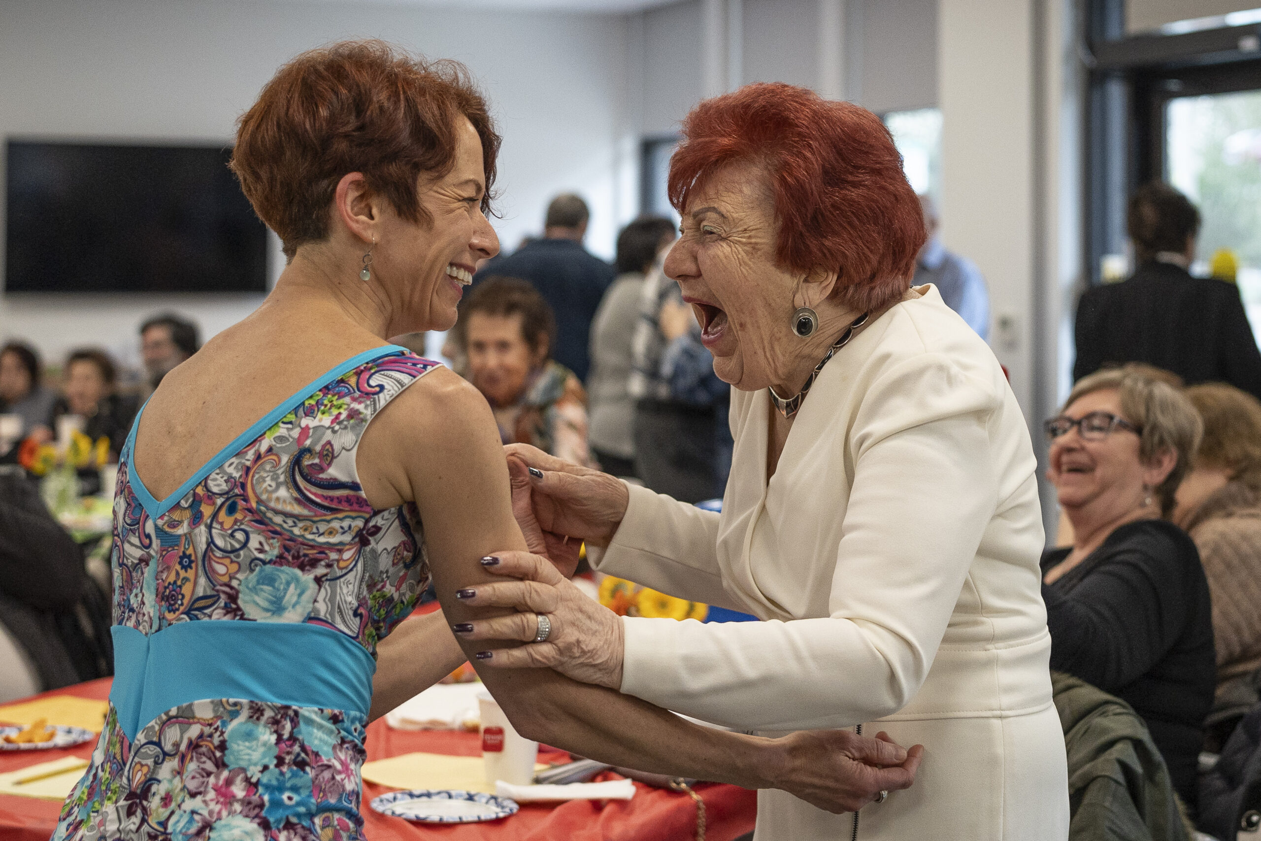 two woman laughing and holding arms