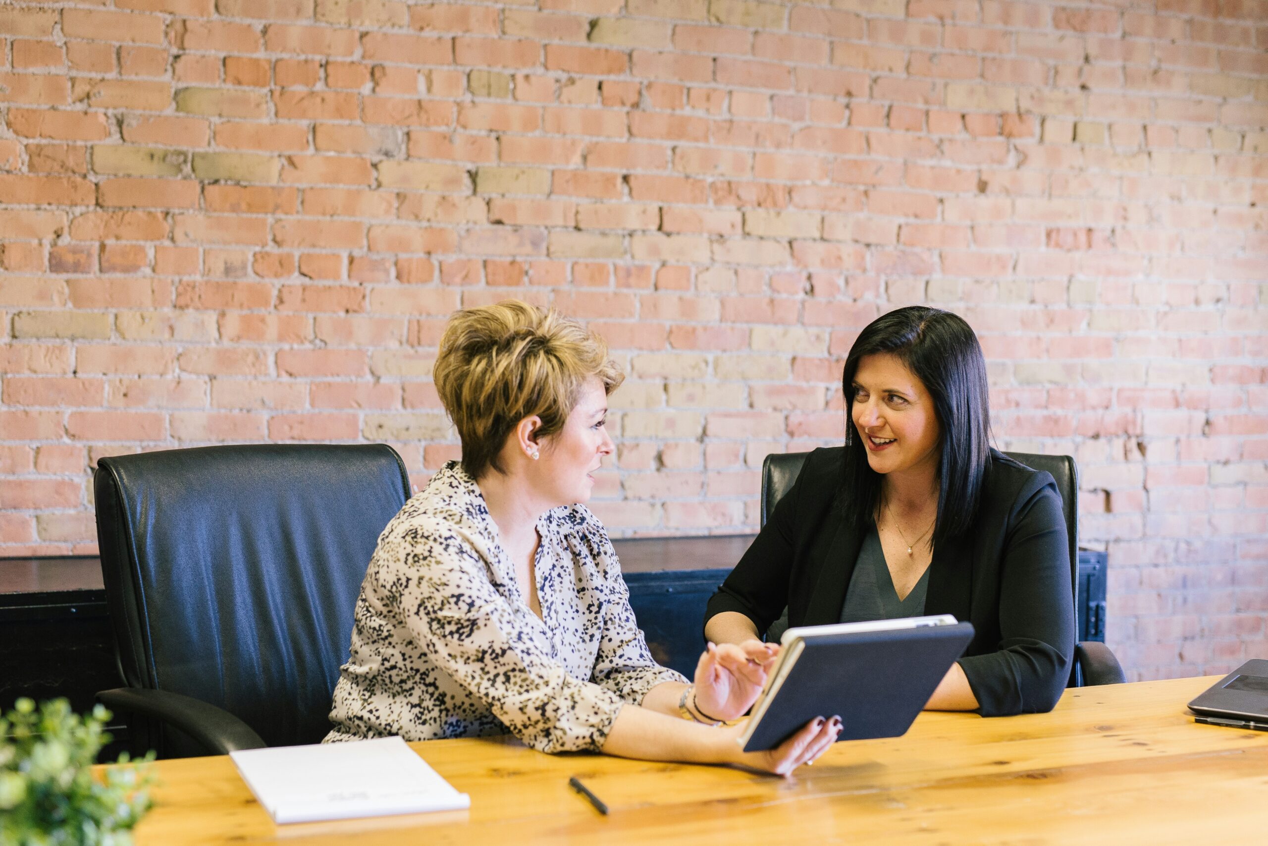 Two women at a desk talking to each other