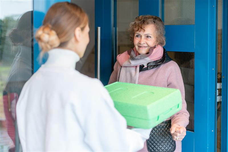 person delivering a meal to an older woman