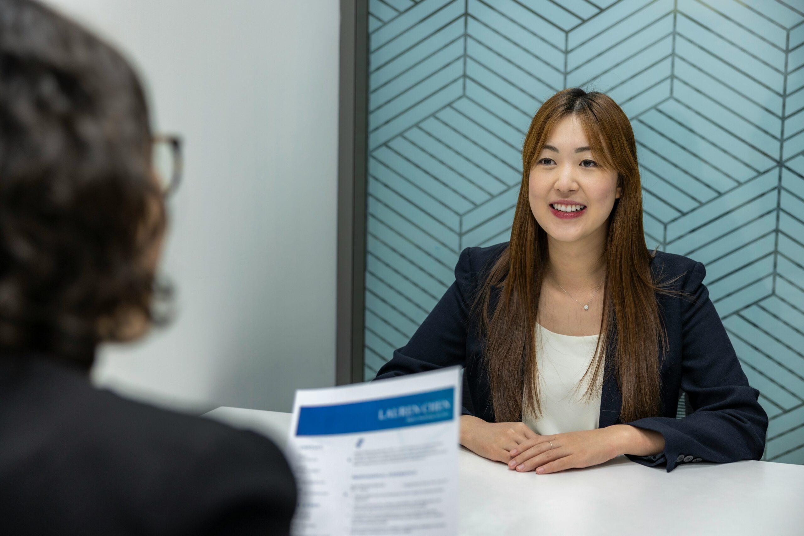 young asian female at a job interview with her interviewer holding her resume
